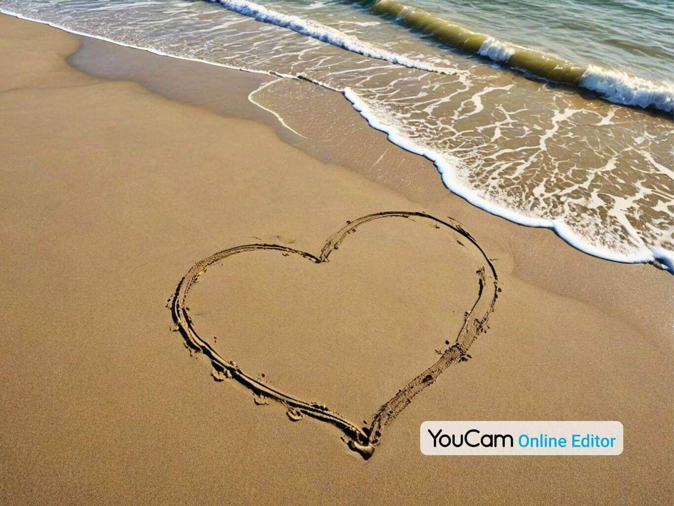 Cœur dessiné dans le sable sur une plage calme avec des vagues douces.
