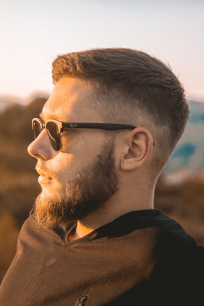 Mann im Profil mit Sonnenbrille und gepflegtem Bart, ein Beispiel für einen stilvollen Look für Männer ab 40.
