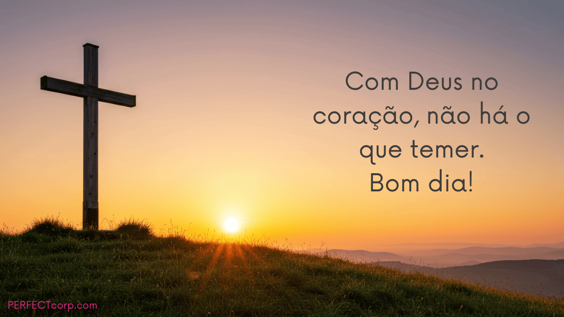 Uma cruz de madeira no topo de um monte gramado com o sol nascendo ao fundo. A mensagem de fé é: "Com Deus no coração, não há o que temer. Bom dia!"