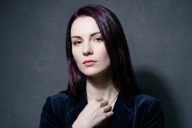 Eine Frau mit der Haarfarbe "Black Cherry", einem eleganten, fast schwarzen Ton mit tiefen, violett-roten Reflexen – ein Winter-Trend 2025/26.