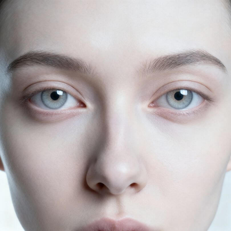 Nahaufnahme Gesicht mit blauen Augen, identische Lichtreflexe in beiden Pupillen wie gespiegelt, perfekte Symmetrie