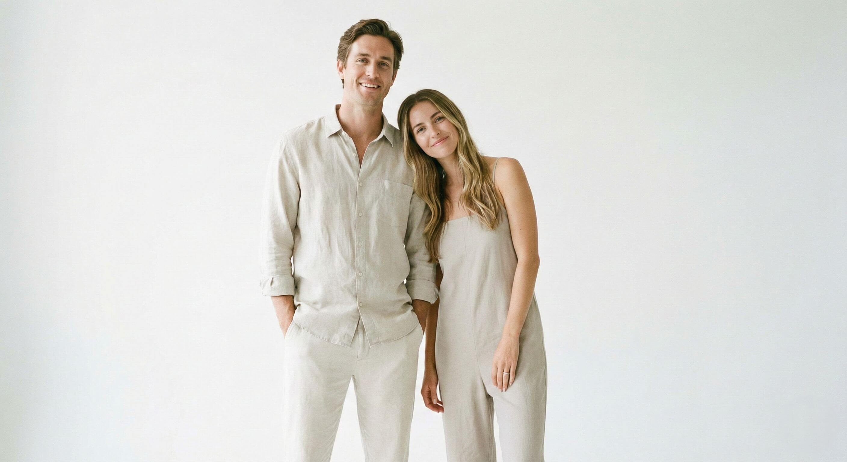 Casal vestindo roupas em tons neutros (bege) em estúdio com fundo branco, exemplo de pose minimalista e elegante para fotos modernas.