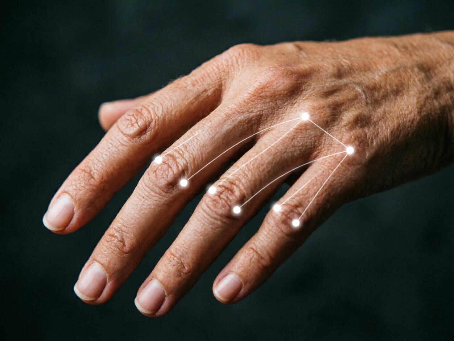 Hand and Finger Detection Photorealistic macro shot of a human hand with a subtle digital tracking mesh made of small white dots and thin connecting lines overlaid across the knuckles and fingers, illustrating AI hand-tracking technology, dark neutral background, tech-editorial lighting style