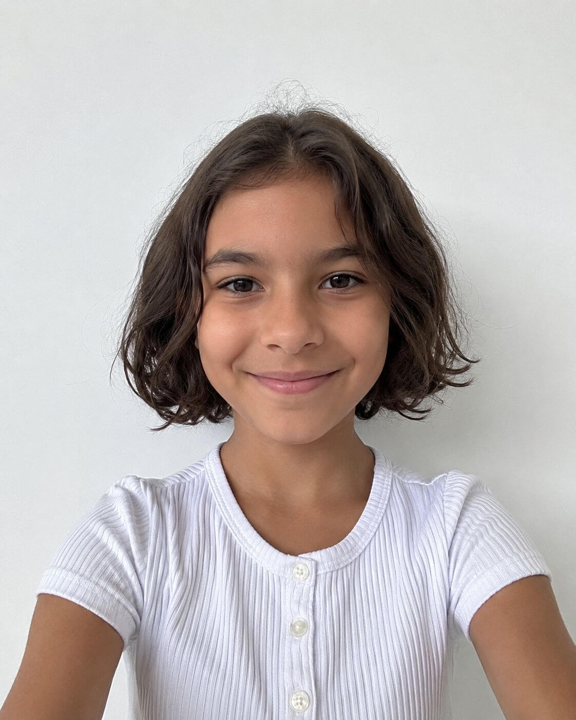 Menina com bob infantil em camadas, cabelo ondulado curto e movimento natural ao redor do rosto.