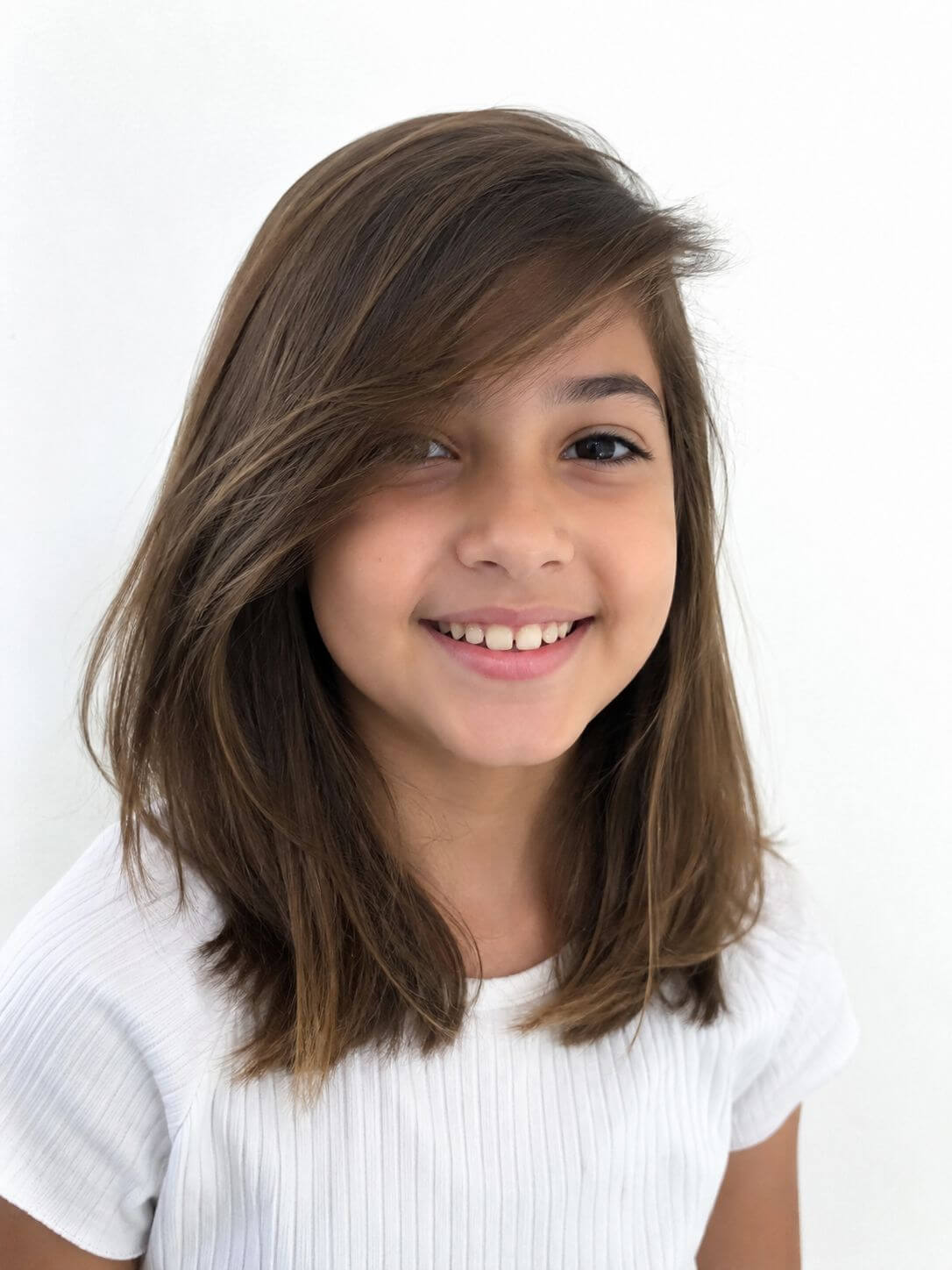 Menina com corte médio e franja lateral longa, penteada sobre a testa, em cabelo castanho.