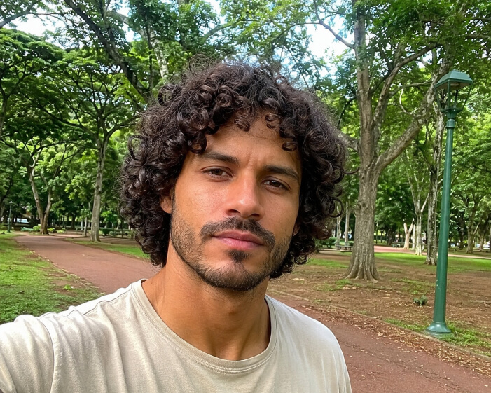 Homem brasileiro com cabelo cacheado médio em camadas e movimento natural
