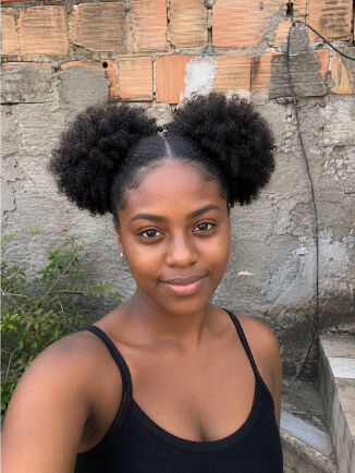 Mulher negra usando afro puffs duplos com risca central e volume natural