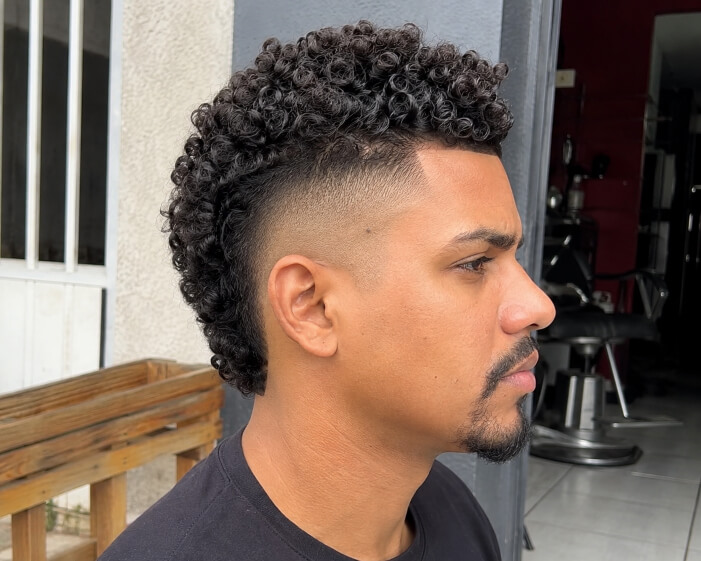 Homem brasileiro com burst fade e moicano cacheado moderno