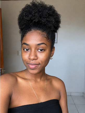 Mulher negra com afro puff alto e volume natural no cabelo crespo