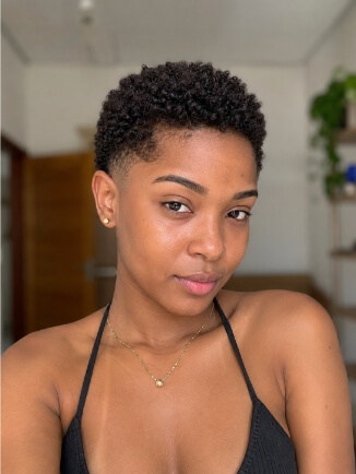 Tapered cut feminino em mulher negra, com laterais curtas e topo crespo volumoso