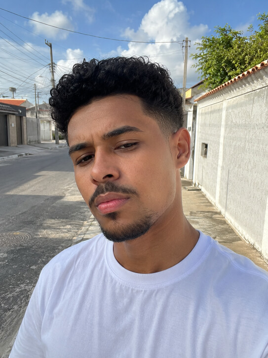 Homem brasileiro com corte low fade e cabelo cacheado curto no topo