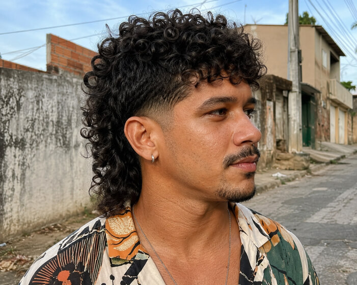 Homem brasileiro com mullet cacheado moderno e comprimento na nuca