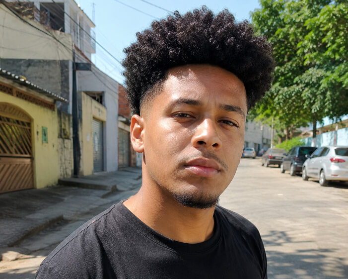 Homem brasileiro com cabelo cacheado alto e degradê nas laterais