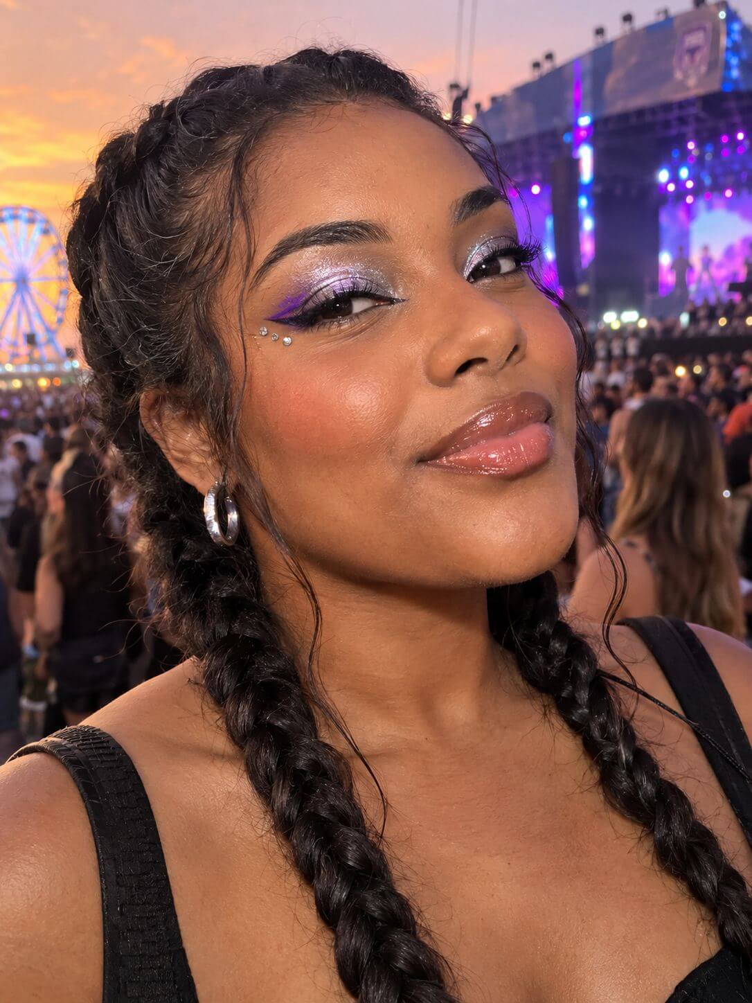 Mulher brasileira com delineado roxo, sombra prata, strass facial e tranças laterais em um festival.