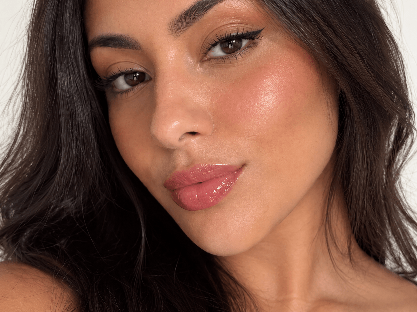 Lábios com efeito juicy lips e brilho de lip oil rosa pêssego.