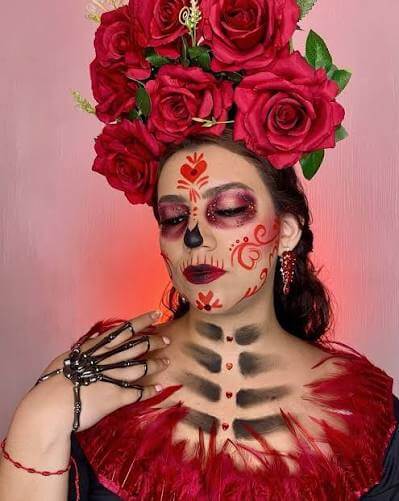 Catrina clásica: Maquillaje de catrina clásico con base blanca, ojos negros con pétalos y labios en tono vino