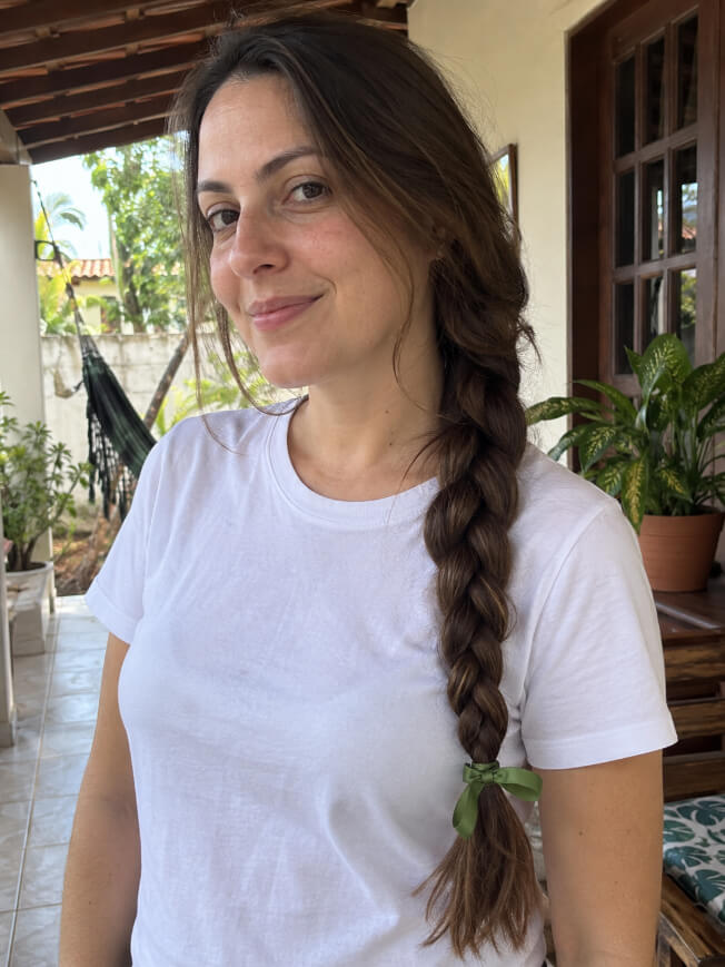 Mulher com trança lateral longa e fita verde como inspiração de penteado para Oktoberfest.