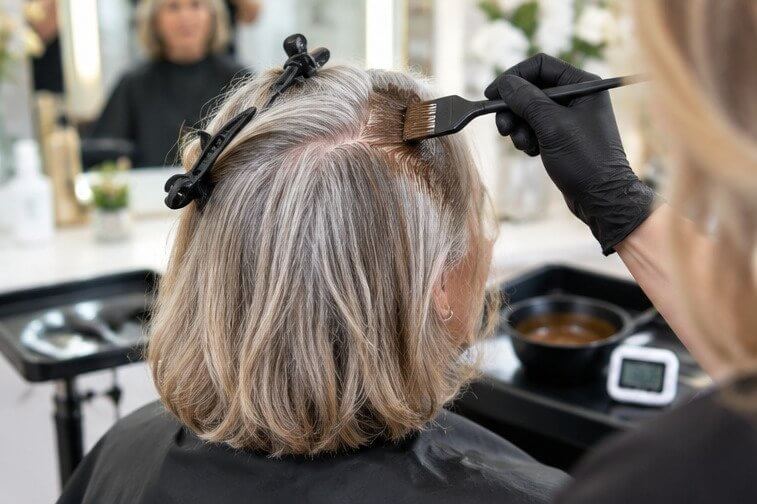 Colorist applying permanent color to gray roots