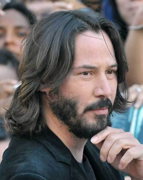 Keanu Reeves mit kinnlangem, glatten braunen Haar und gepflegtem Bart, klassischer mittellanger Männerhaarschnitt ab 50.