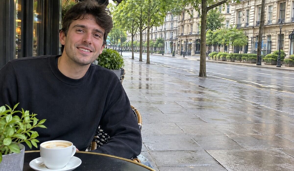 Same man at the cafe table after the pedestrians and cyclist were removed, leaving an empty street